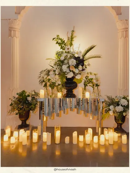 An elegant vignette with a floral arrangement on a mirrored console table, surrounded by a sea of candles, creating a moment of quiet glamour amidst the party.