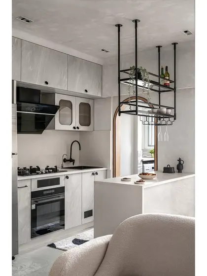In the 'Unmei' kitchen, a breakfast counter and a custom-suspended bar unit create a subtle separation from the living area. I used full-body tiles that blend with the wall and textured laminate for a subtle contrast, maintaining the home's minimalist and functional aesthetic.