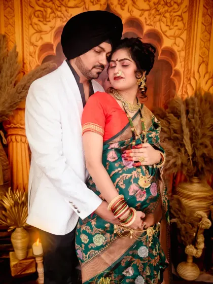 An elegant couple's pose during their traditional Indian-themed maternity session. The warm lighting and ornate background create a rich, cultural feel.
