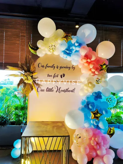 A sweet and modern baby shower or gender reveal backdrop. The pastel blue and pink balloon arrangement is complemented by a personalized message celebrating the family's new arrival.