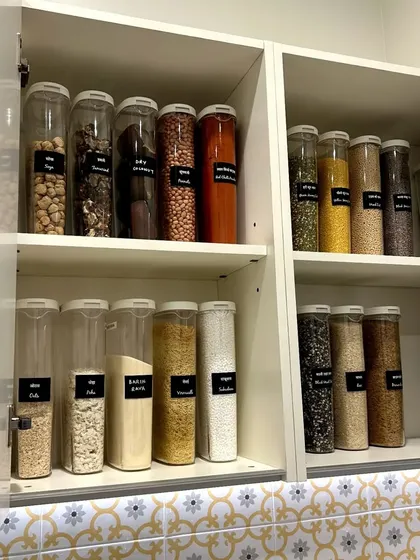 A beautiful pantry cabinet with clear, labeled containers. This setup is perfect for storing various flours, grains, and pulses, keeping them fresh and easy to identify.