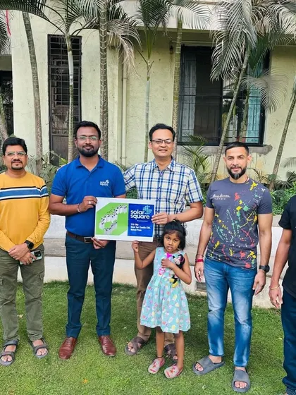 A housing society committee, including a young girl, proudly holds our welcome kit after deciding to go solar.