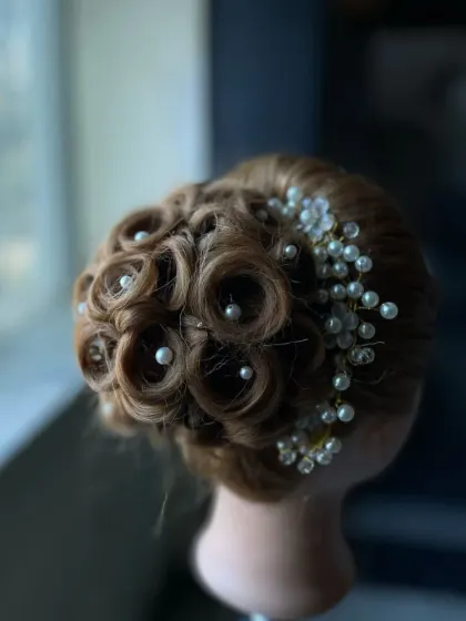 An intricate updo featuring beautifully crafted pin curls, each centered with a pearl. This advanced styling technique is perfect for creating a sophisticated and glamorous look.