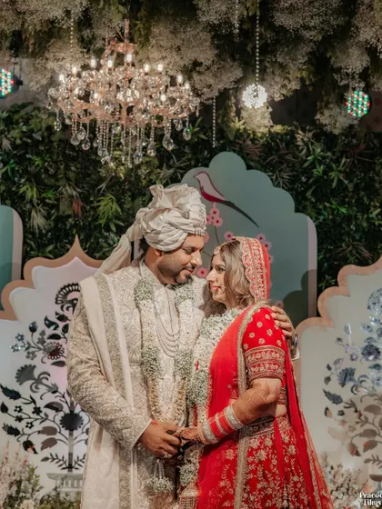 An intimate portrait of the couple under a grand chandelier after their Varmala ceremony, their loving gaze telling a story of forever.