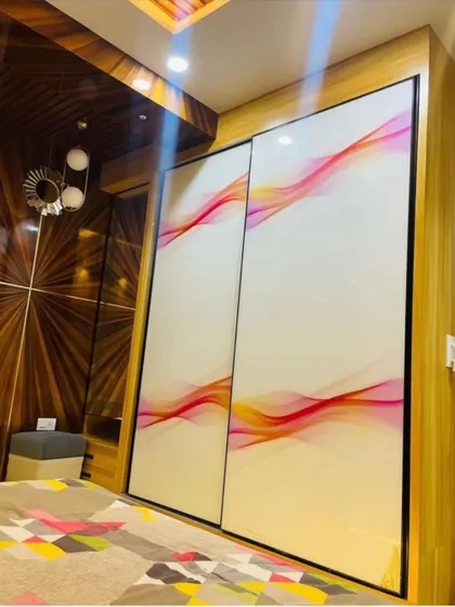 A premium sliding wardrobe with printed glass shutters. The abstract wave pattern on the glass adds a unique, artistic element to the bedroom.