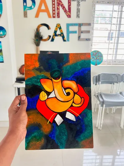 A vibrant and abstract Ganesha painting on canvas, held up in the studio.