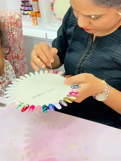 A student shows off her practice wheel, filled with a variety of colorful and creative nail art designs.