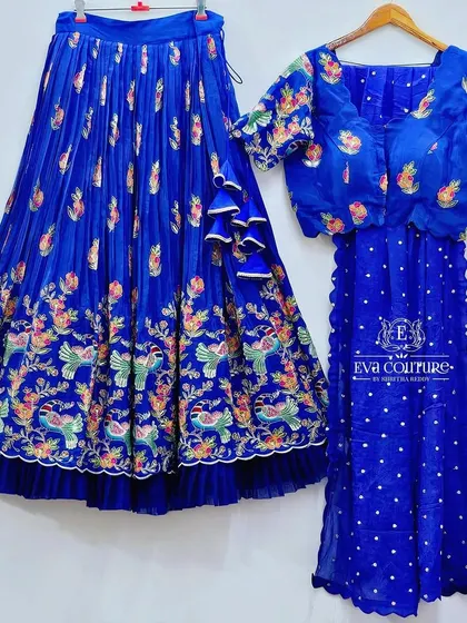 A royal blue lehenga set with a Paithani-style embroidered border. The skirt and blouse feature colorful peacock and floral embroidery.