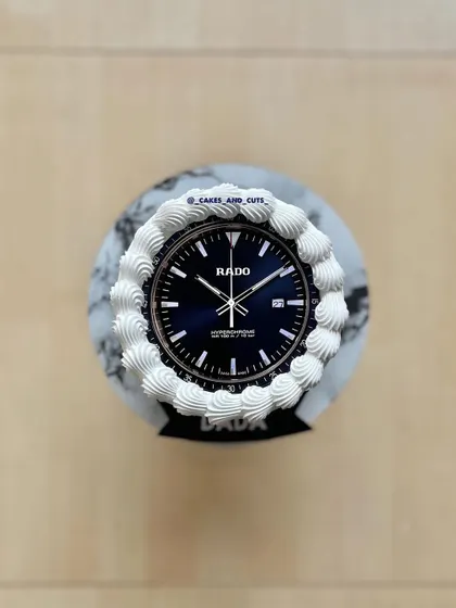A top-down view of the Rado cake, highlighting the detailed watch face and piped border.