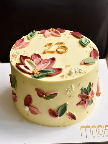 An elegant custom cake marking a 23rd birthday or anniversary, featuring beautifully piped lotus flowers and leaves in soft, artistic tones. This design shows how we can tailor our floral work to any occasion.