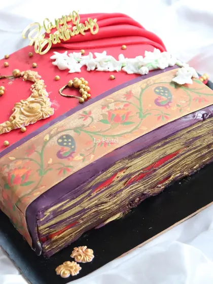 A close-up on the corner of the Paithani cake, highlighting the texture and shimmer of the golden border and the delicate layers of the saree folds.