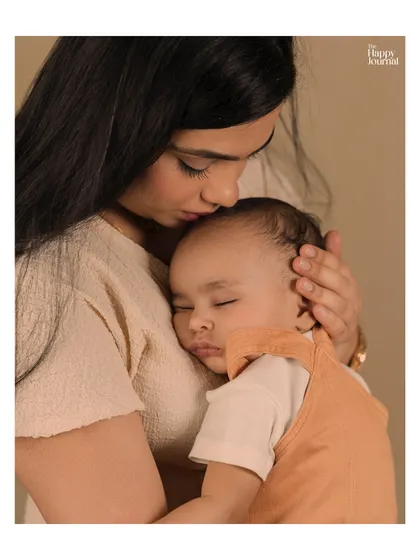 A mother holds her sleeping baby close, a moment of pure peace and tenderness. The soft focus and warm tones enhance the feeling of love and security.