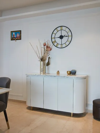 This contemporary sideboard with a marble top and clean, modern design is styled with a large wall clock and decorative items for a minimal yet chic appeal.