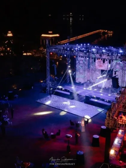 An aerial view of the massive concert-style stage set up for the Yayoi Kusama-themed sangeet. This shot highlights the scale of our production capabilities, set against the beautiful Udaipur lake.
