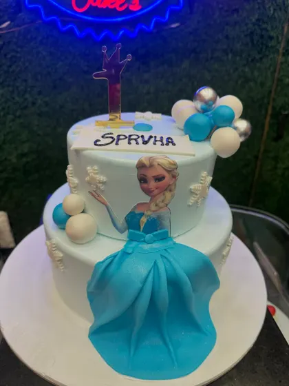 Let it go! This Frozen theme cake features Elsa with a flowing blue fondant dress. The snowflake and balloon details add to the wintery magic of this popular theme.