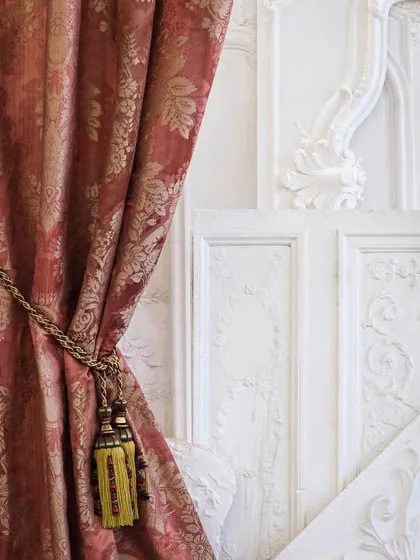 The 'Foscarini' fabric by Nobilis, used here as a grand curtain. The delicate floral damask pattern, woven with a sophisticated strié warp, adds a touch of timeless charm and classical elegance to the room.