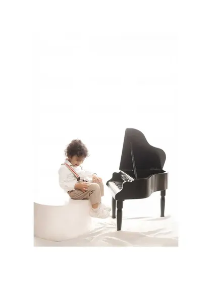 The young pianist looks down at the keys, seemingly lost in thought. This candid moment adds a layer of narrative to the studio session, capturing a quiet and contemplative side of his personality.