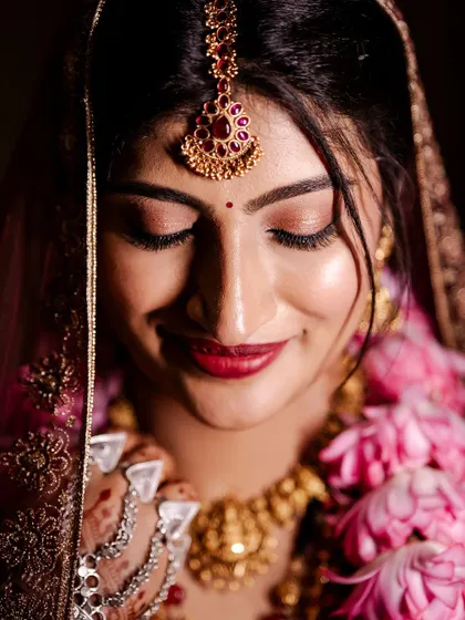 A detailed close-up of the bride's makeup. The soft, shimmery eyeshadow and bold red lip create a stunning, classic bridal look.