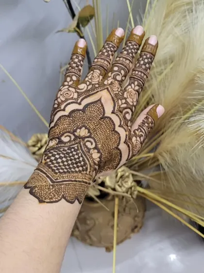 A detailed design on the back of the hand, featuring a mix of checkerboard fill (jaali) and delicate floral work.