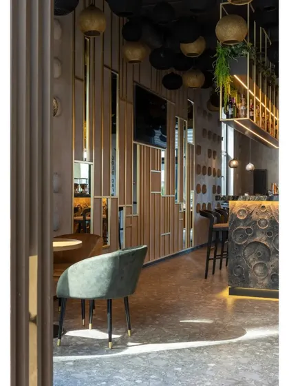 This view highlights the use of mirrored and slatted wood panels as a space divider, adding depth and visual interest. The design plays with reflection and texture to make the space feel larger.