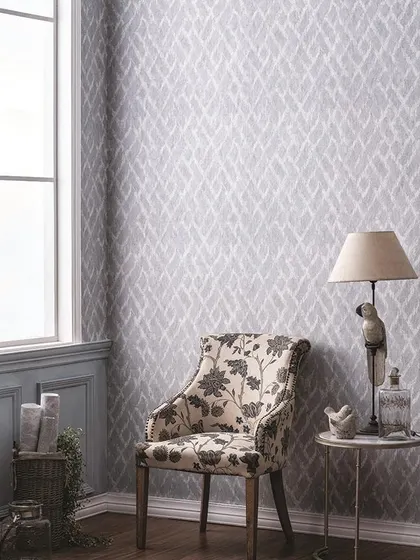 A beautiful corner showing a subtle, grey patterned wallpaper that complements the floral armchair. Mixing patterns can work wonderfully when the color palette is cohesive.