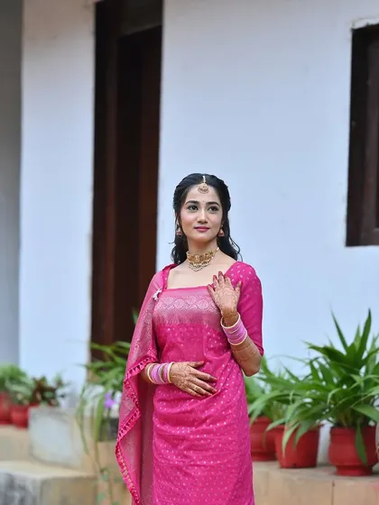 A portrait of a bride in a pink saree for her Oorkuduva ceremony. Her makeup is soft and natural, and her hair is styled in loose waves.
