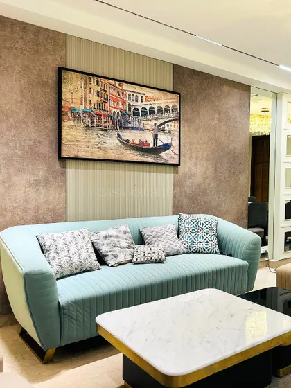 A comfortable seating arrangement with a light blue sofa, accented with patterned cushions. The large painting of a Venetian canal adds a touch of classic art to the modern space.