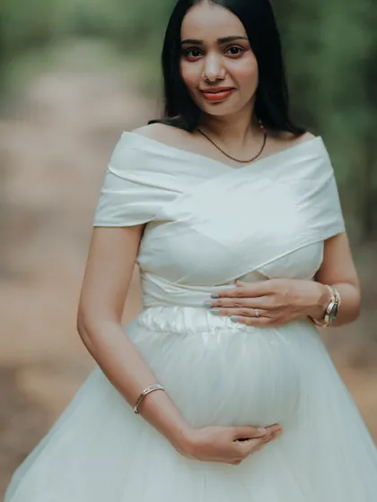 A beautiful portrait of a mom-to-be, cradling her bump. The satin-finish bodice of this white gown adds a touch of luxury.