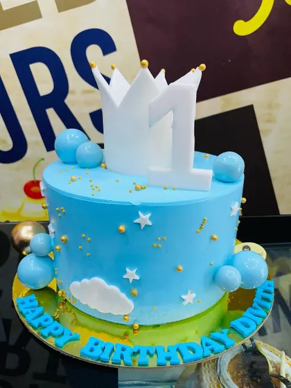 A royal blue 2kg cake for a first birthday, topped with a number one and a crown.