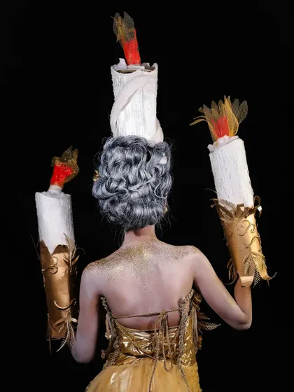 The back view of the candle-themed fantasy look, showing the intricate hairstyle and costume details.