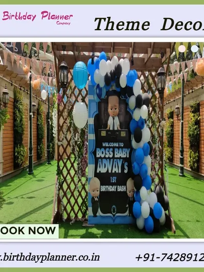 An outdoor Boss Baby theme entrance for Advay's first birthday bash. A custom welcome sign is framed by a wooden trellis and a blue, black, and white balloon arch.