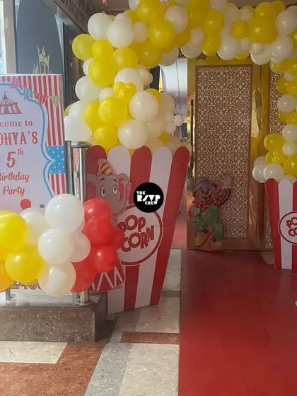 A classic carnival entrance with a red carpet, popcorn-themed decor, and a welcome sign for Aadhya's 5th birthday.