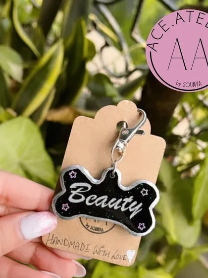 A chic and stylish dog tag for a pet named Beauty. This black resin, bone-shaped tag features a silver border and sparkly star details.