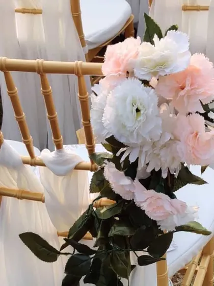 A beautiful detail of the guest seating. We decorated the gold chiavari chairs with flowing white drapes and a small bouquet of pink and white carnations.