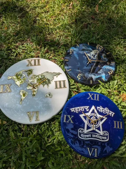This image shows three distinct custom wall clocks together: the world map, a Shivji galaxy theme, and the Maharashtra Police logo. Each one is made with a glossy resin finish on an MDF base.