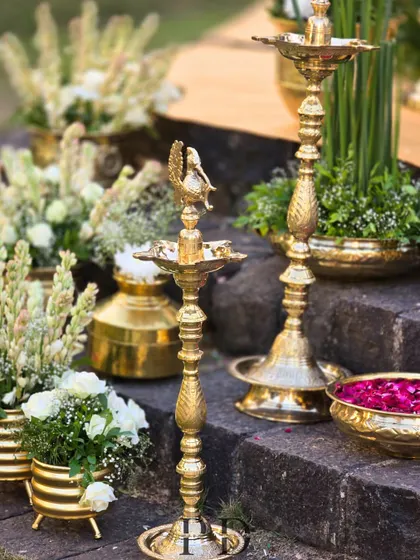Traditional South Indian brass lamps ('diyas') used as decor elements, adding an authentic and sacred glow to the wedding ceremony.