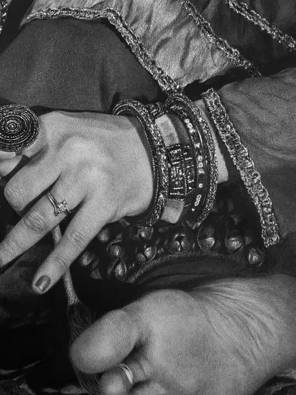 A detailed shot of the dancer's hand, adorned with rings and bangles, resting near her foot. This composition emphasizes the ornamentation of classical dance.