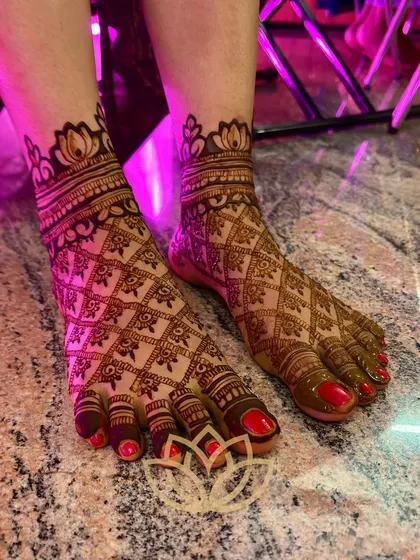 A close-up of the bride's feet, featuring a beautiful geometric pattern with a lotus border.