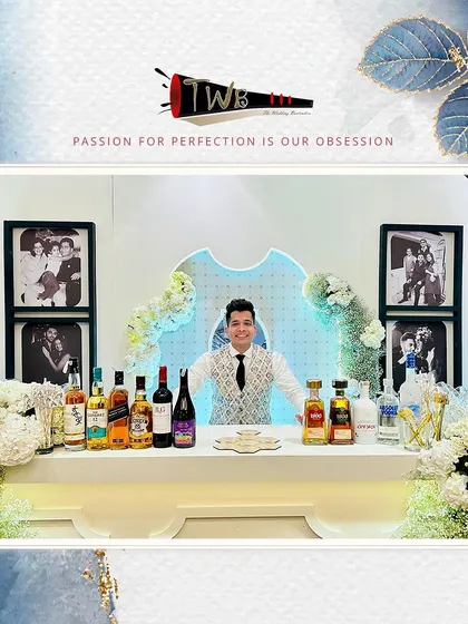 A classic and stylish bar setup for a reception at The Leela Palace, featuring clean white decor, elegant floral arrangements, and professional backlighting to showcase our premium liquor selection.