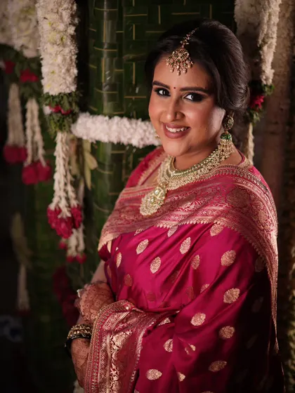 A radiant portrait of the bride. The soft lighting and the traditional floral decor in the background enhance her bridal glow, showcasing how my designs create perfect photo moments.