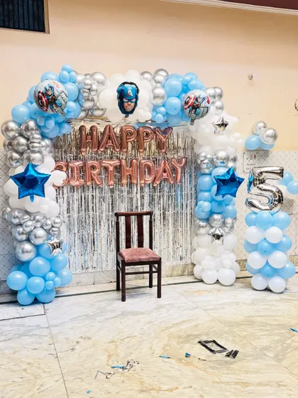 A superhero-themed birthday party featuring Captain America. The balloon arch in blue, silver, and white creates an exciting backdrop for a 5th birthday.