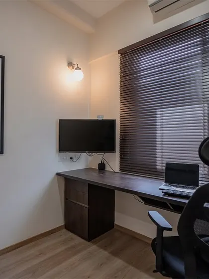 A simple and effective home office setup with a long desk providing ample workspace. The vintage poster adds a touch of personality to the functional design.
