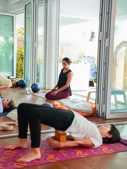 Guiding a student through a supported backbend during a class. This shows the blend of group energy and individual attention that I strive for in my teaching.
