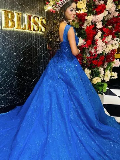 A view of the back of our royal blue sequined ball gown. The dress features a low back and a full, sparkling skirt.