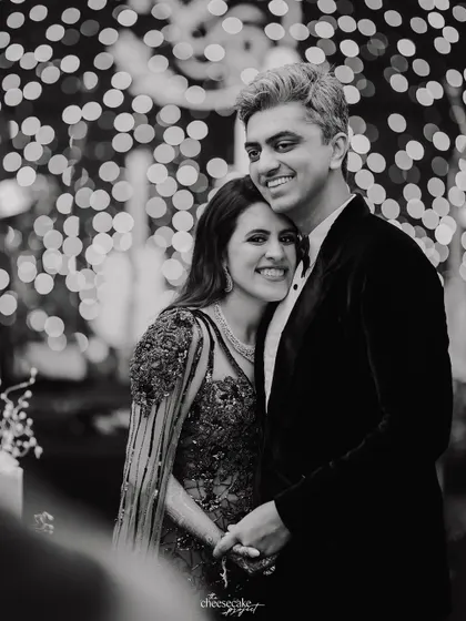 A sweet, smiling portrait of the couple during their cocktail night, with a beautiful bokeh background of fairy lights.