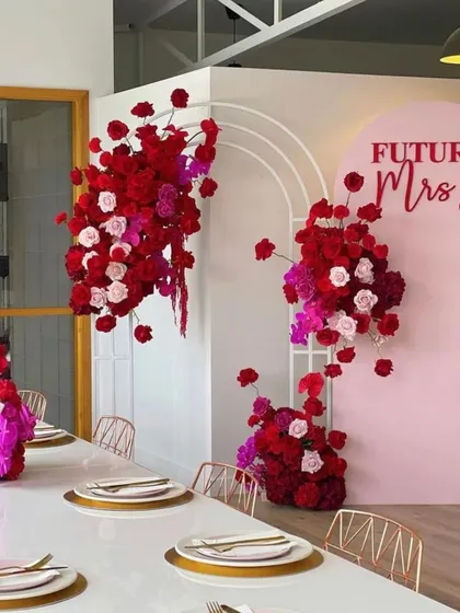 A chic and modern bridal shower setup with a "Future Mrs B" sign. The clean lines, long table, and stunning red and pink floral arrangements create a sophisticated and celebratory atmosphere.
