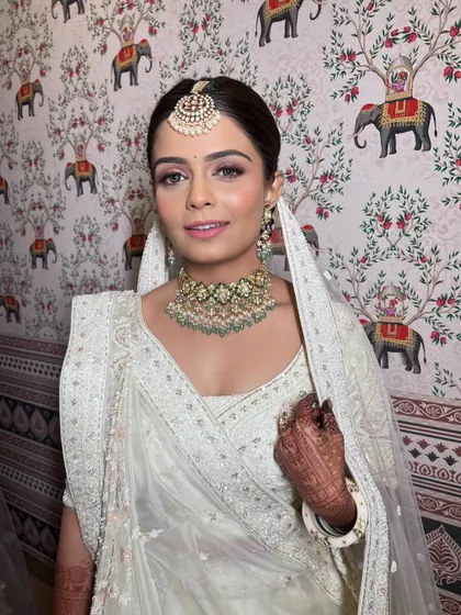 A close-up portrait showing the soft, blended makeup that complements her white outfit and polki jewelry perfectly.