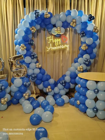 Here is a grand heart-shaped balloon arch I created for a 25th anniversary celebration. The blue and silver color scheme, combined with the large '25' foil balloons and a 'Happy Anniversary' neon sign, makes for a perfect photo backdrop at any party venue.