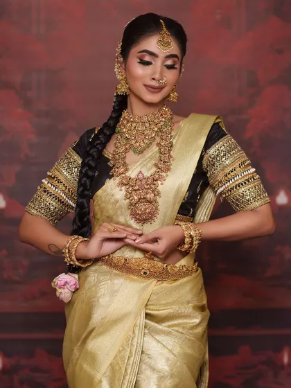 A full-length view showing the beautiful drape of the golden silk saree and the traditional braided hairstyle adorned with flowers.