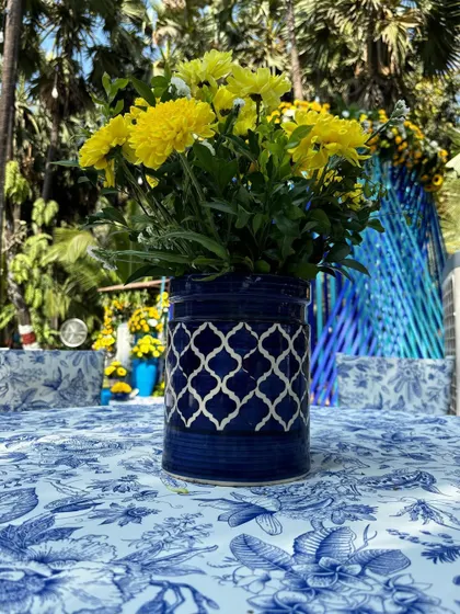 A simple, modern blue ceramic vase with a geometric pattern, filled with yellow flowers, part of the cohesive table decor.